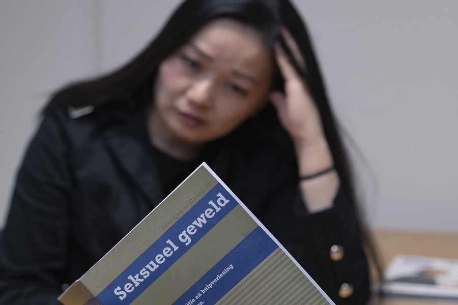 Boekje 'seksueel geweld' in beeld met op achtergrond vrouw met lang donker haar