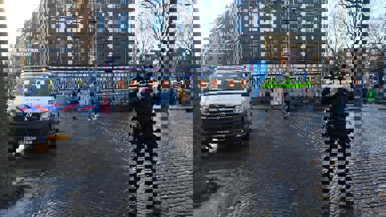 Jovanny op de Nieuwmarkt in Amsterdam met een politieauto
