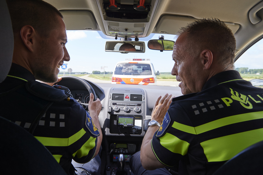 Twee agenten vanaf de rug gezien zijn bestuurder en bijrijder van politiewagen