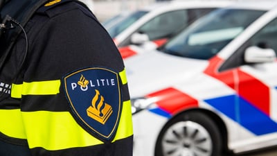 Embleem politie met politieauto's op de achtergrond