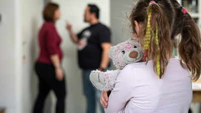 A child with a cuddly toy hugged looks at arguing parents