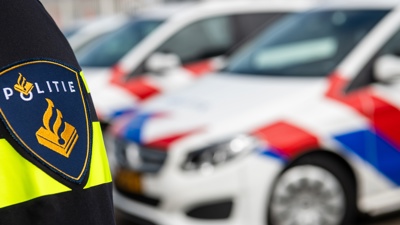 De mouw van een politie-uniform en twee politieauto's.