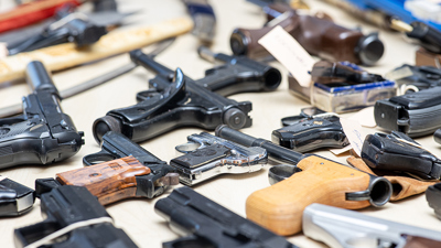 Several weapons lie next to each other on the table after a weapons surrender campaign