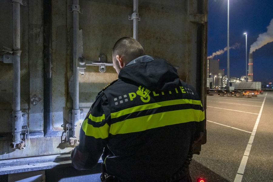 Politieacademie studierichting Mensenhandel en migratiecriminaliteit - agent vanaf de rug gezien staat bij achterzijde vrachtwagen 