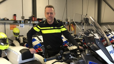 Docent Ben staat in een garage tussen politiemotoren