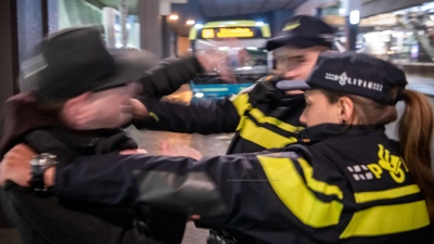 Twee agenten in een handgemeen met een man met een stadsbus op de achtergrond