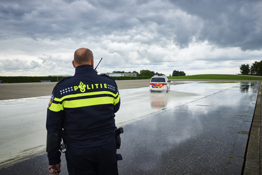 Politieacademie studierichting Politierijinstructeur - Agent kijkt naar politiewagen op slipbaan