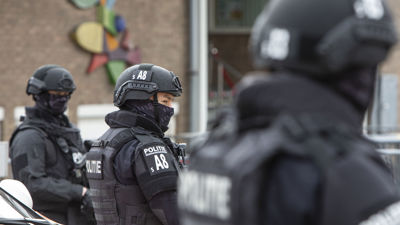 Drie agenten in zwart pak met helm bewaken en beveiligen een locatie