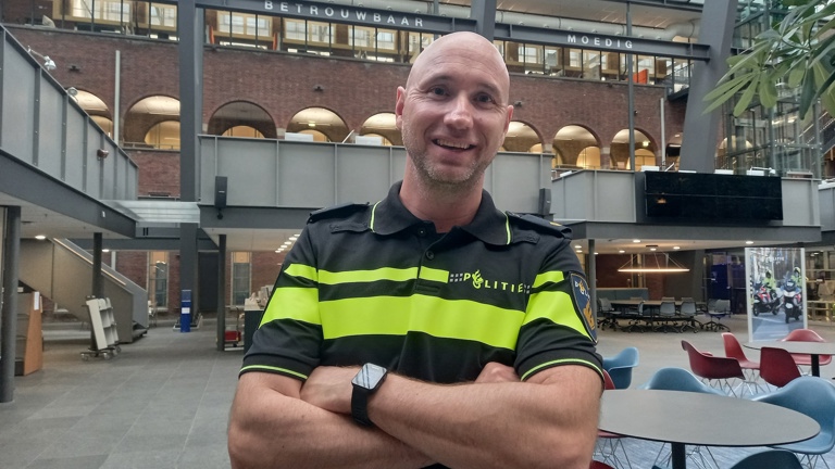 Docent Daniël staat in het atrium van de Politieacademie in Apeldoorn