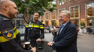 Lector Otto Adang in gesprek met twee politiestudenten in het atrium van de Politieacademie in Apeldoorn