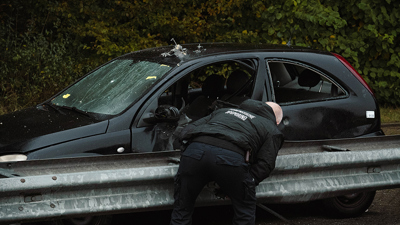 Zwarte geëxplodeerde auto langs de vangrail met iemand van de Forensische Opsporing