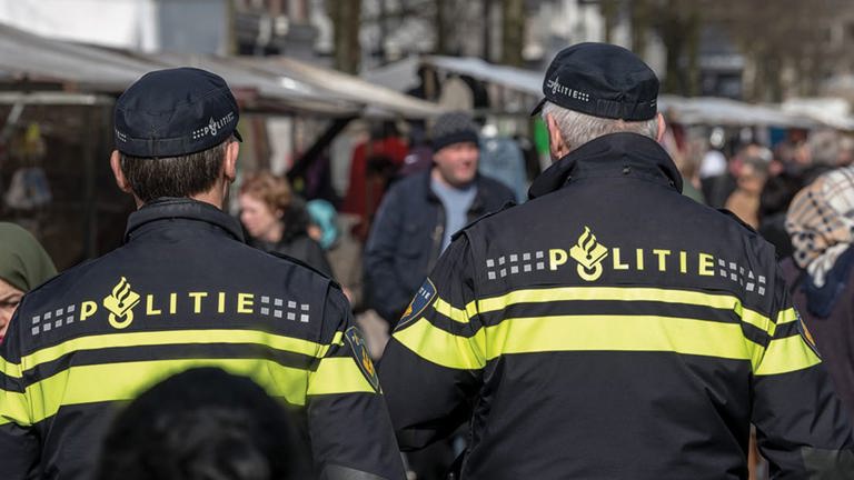 Vraagarticulatie in verre uithoeken - Twee agenten op de rug gezien lopen op markt