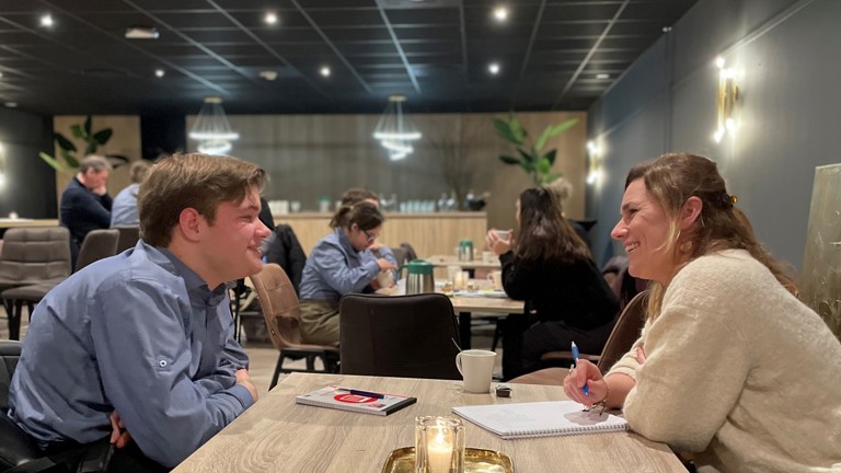 Een verhoorstudent en een student van Parc Spelderholt tegenover elkaar aan tafel.